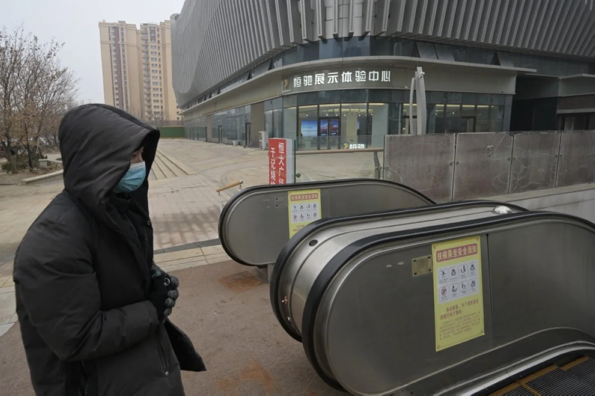 BEIJING: A woman walks past the Hengchi car showroom at a partially operating Evergrande commercial complex in Beijing.- AFP