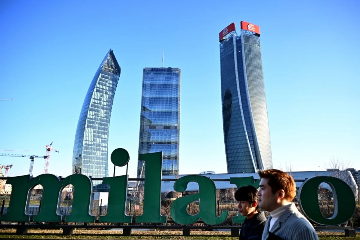 MILAN: People walk past giant letters reading ‘milano’ with skyscrapers of the CityLife district in the background in Milan. The CityLife district is a residential, commercial and business district, with three skyscrapers: Il Curvo (The Curved One) (left), Il Dritto (The Straight One) – Allianz Tower (center) and Lo Storto (The Twisted One) – Generali Tower. - AFP