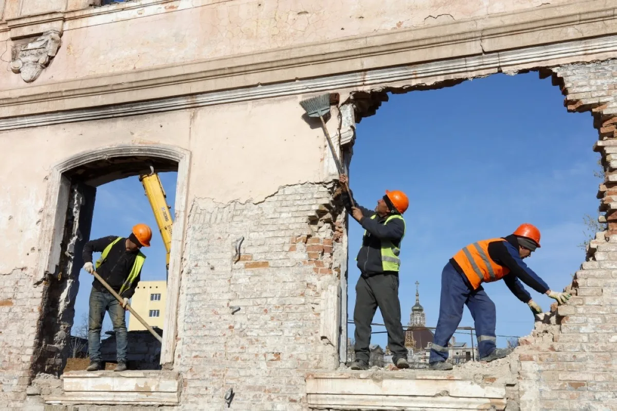 MARIUPOL: Construction workers clean the wall of a house to be restored in Mariupol, Russian-controlled Ukraine.- AFP