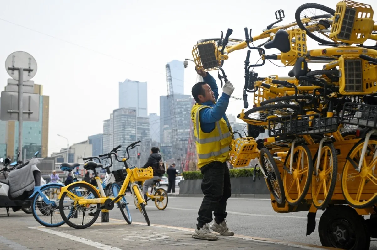 BEIJING: A worker unloads sharing bicycles along a road in Beijing.- AFP