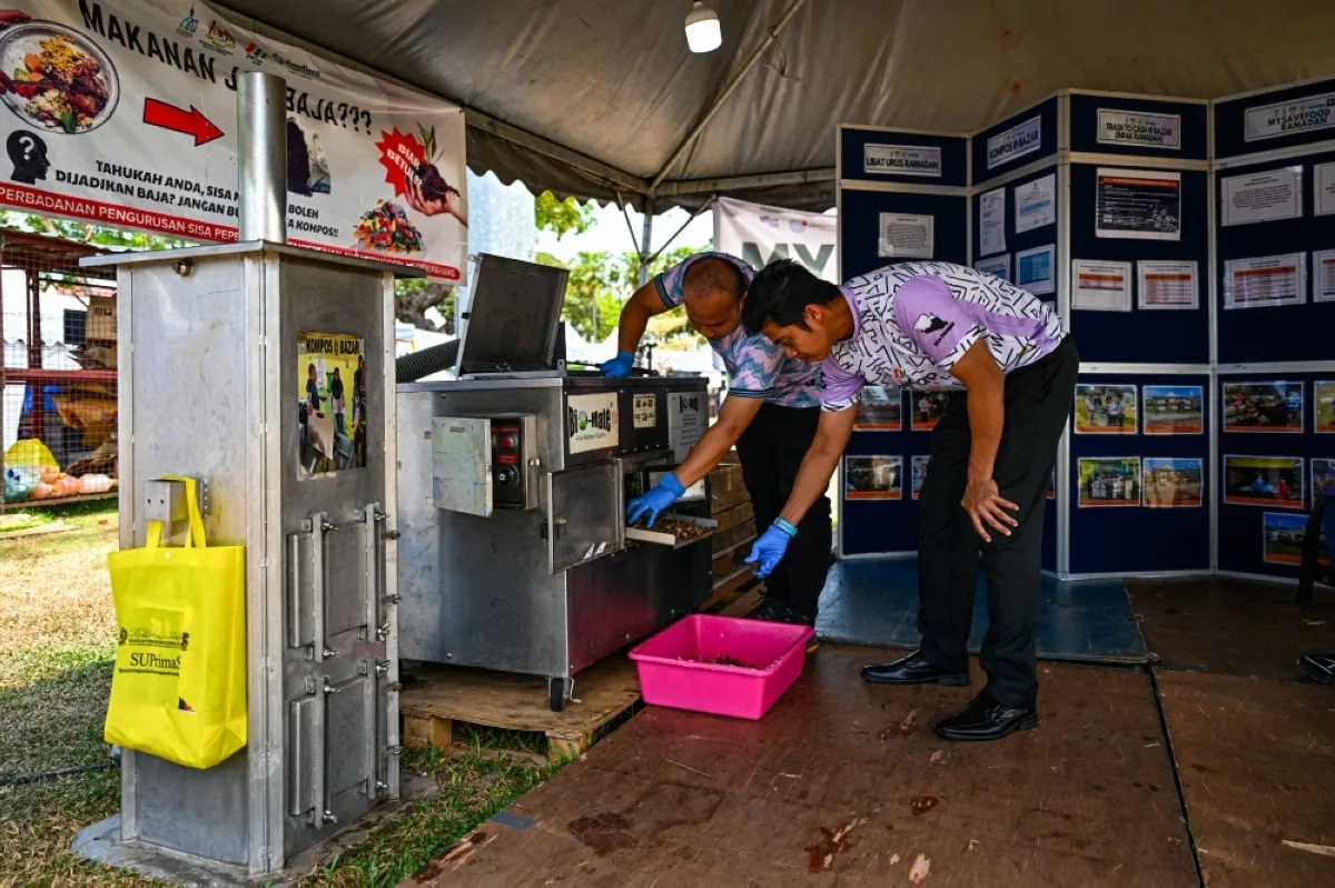 KUANTAN: Two members of the Pahang Solid Waste and Public Cleansing Management Corporation inspecting organic fertilizer, processed by a composting machine in Kuantan, Malaysia’s Pahang state. – AFP