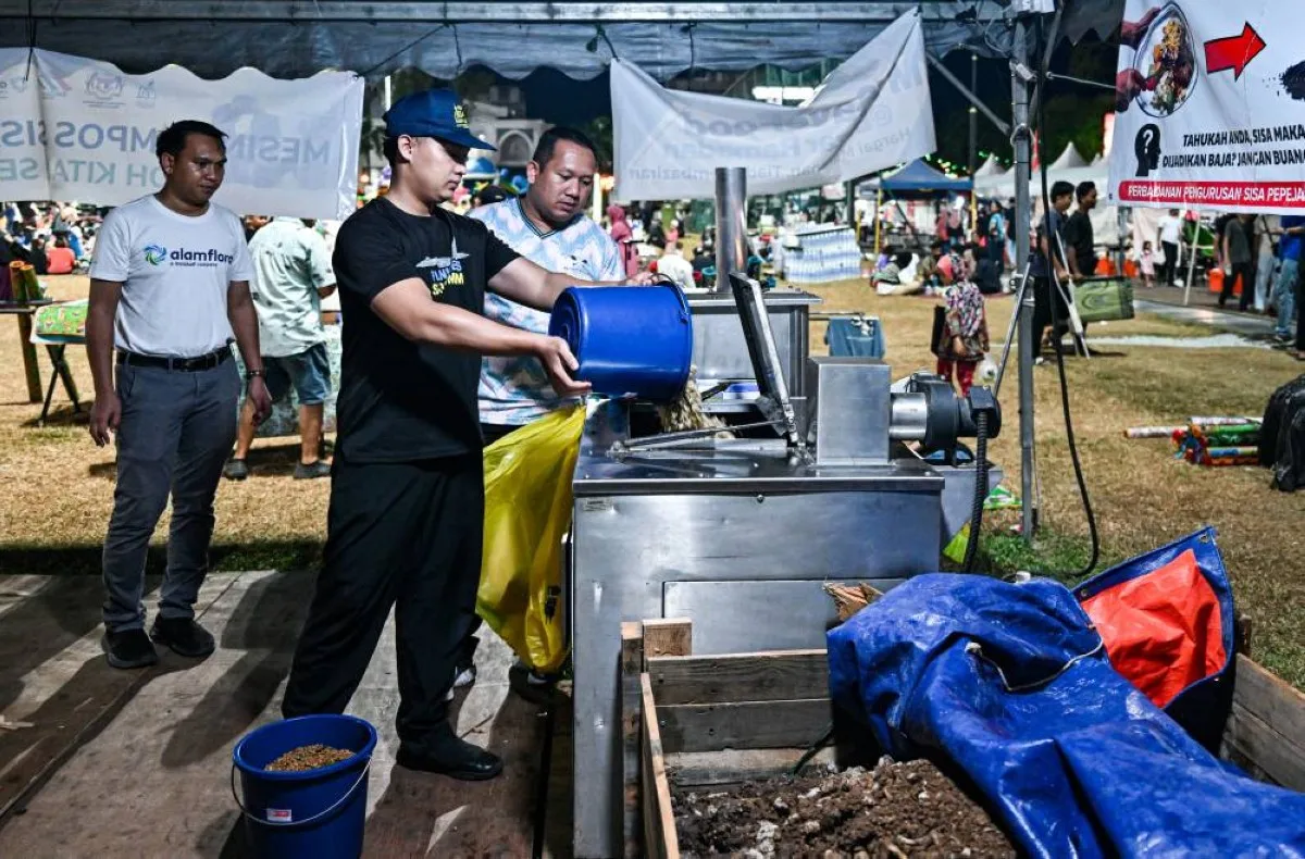 KUANTAN: A Ramadan bazaar trader throws food waste into a composting machine in Kuantan, Malaysia’s Pahang state. – AFP