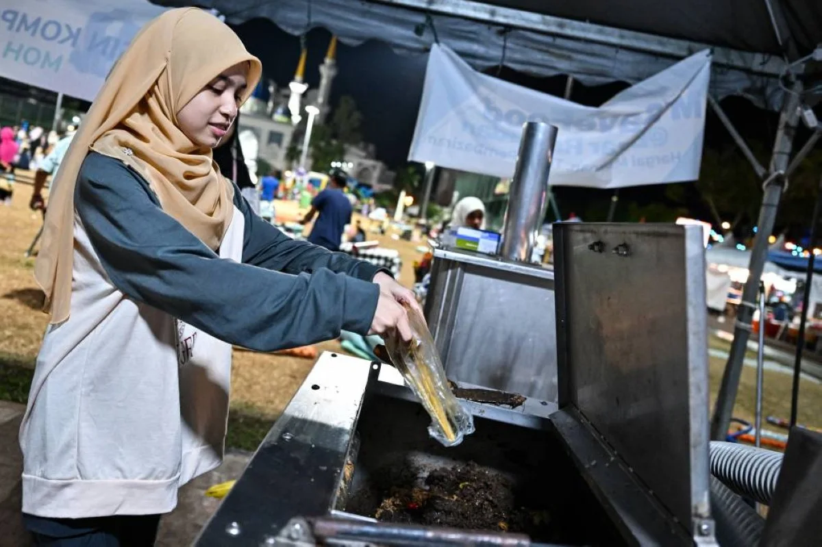 KUANTAN: A woman throws food waste into a composting machine in Kuantan, Malaysia’s Pahang state. – AFP