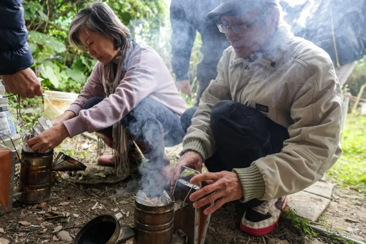 Tsai Ming-hsien (right), the instructor of an urban beekeeping class of Yonghe community college, shows students how to set up a smoker during a class in New Taipei City.