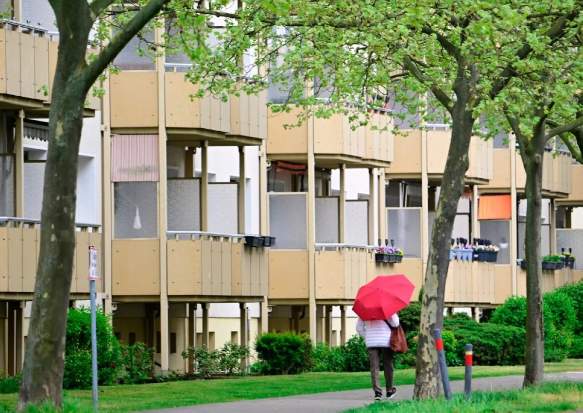 ORANIENBURG: A woman with an umbrella walks past a social housing complex in Oranienburg, north of Berlin, Germany.- AFP