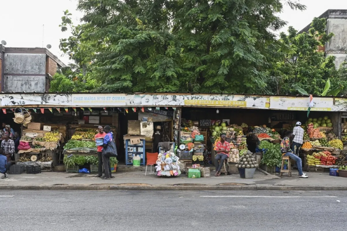 ABIDJAN: Men sit in front of the Cocody fruits and vegetables market in Abidjan.- AFP