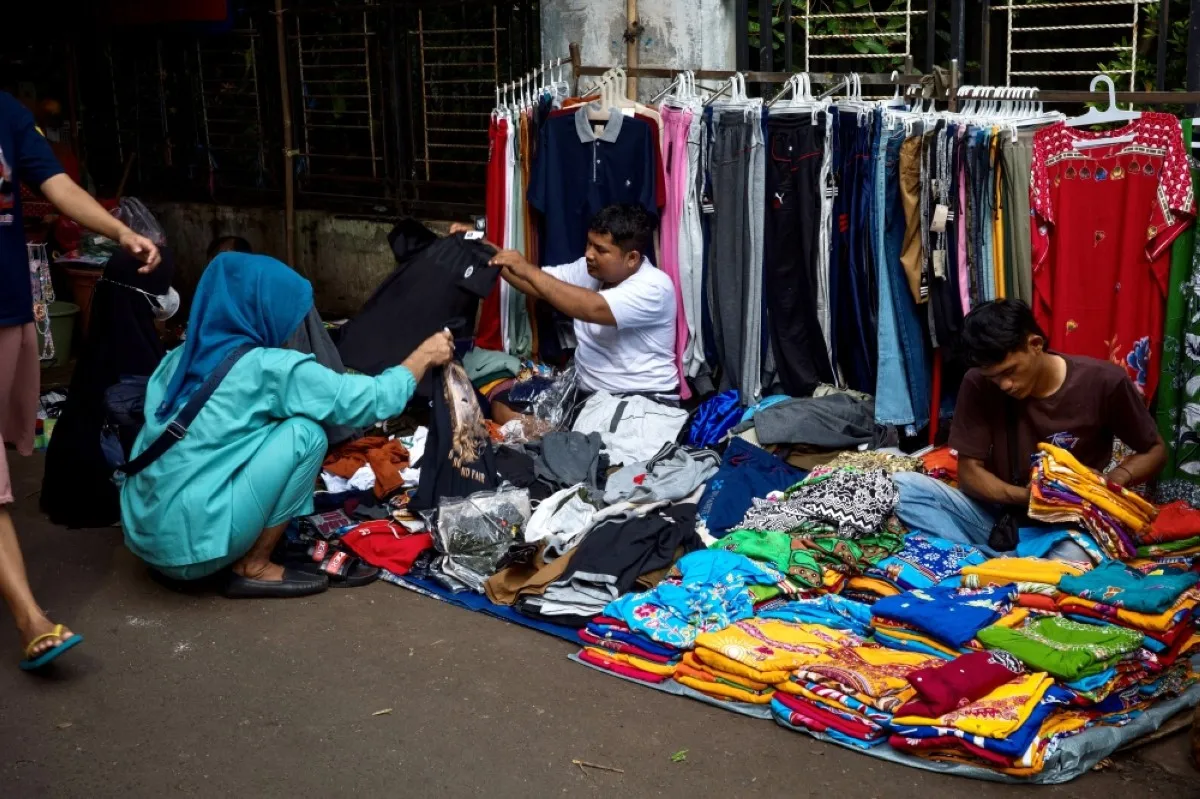 JAKARTA: Indonesian woman chooses clothes to purchase from a street vendor at a traditional market in Jakarta. – AFP