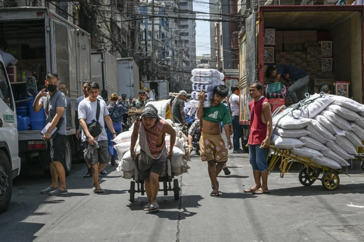 MANILA: Men pull a trolley of agricultural products along a street in Manila.- AFP