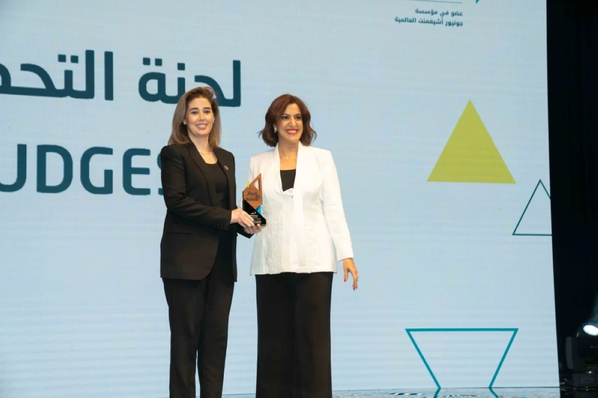 Najla Al-Eisa receives an honorary shield from Laila Hilal Al-Mutairi.