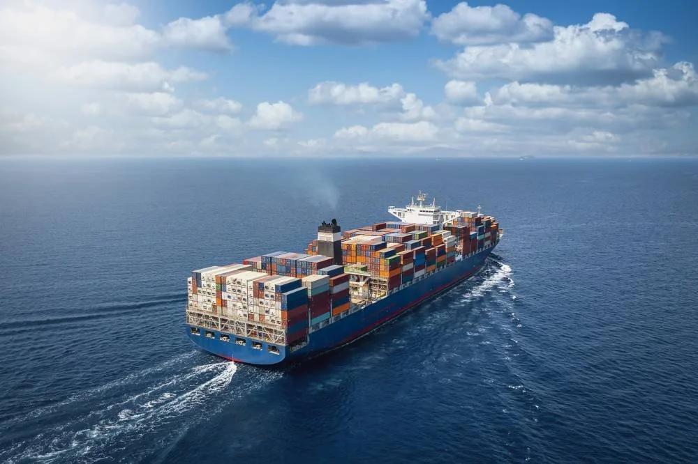 A large container cargo ship travels over calm, blue ocean