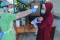 مسعف في أحد المراكز الفلسطينية يقيس حرارة سيدة تحمل طفلا رضيعا بعد ارتفاع عدد الإصابات بكورونا