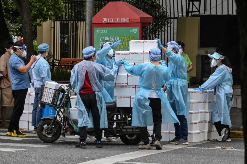 Workers wearing protective gear stack up boxes over a cart to deliver in a neighborhood during a Covid-19 coronavirus lockdown in the Jing'an district in Shanghai on May 18, 2022. — AFP pic