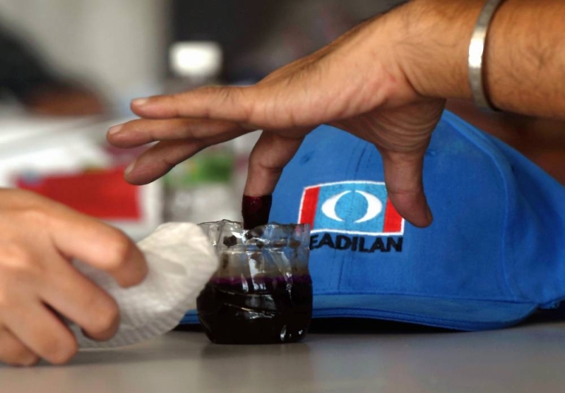 A PKR supporter dips her finger into the ink prior to casting her vote at the PKR 2022 poll in Shah Alam, May 21, 2022 ― Bernama pic