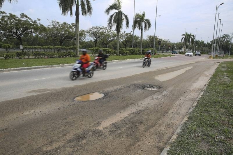 File picture of motorcycles passing by some potholes near Cyberjaya. — Picture by Yusof Mat Isa