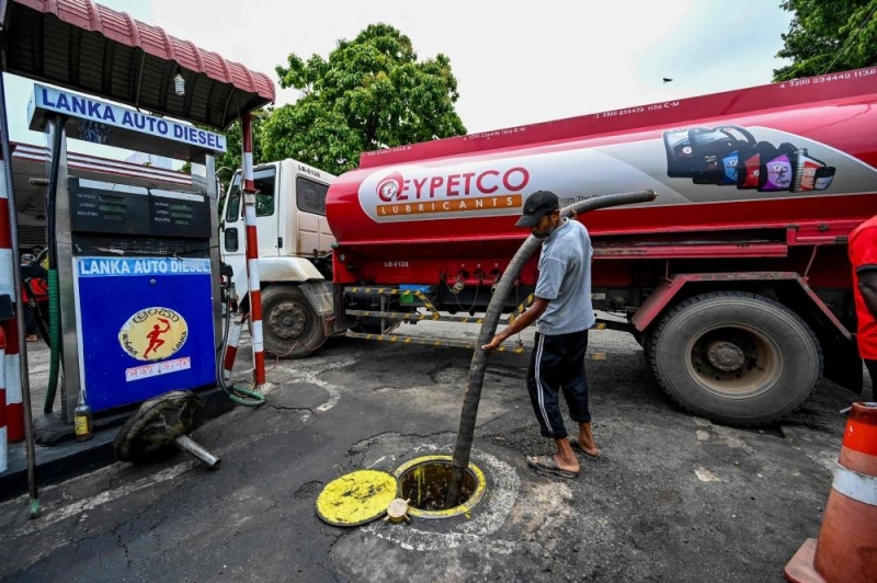 An employee prepares to transfer petrol from a tanker truck to a Ceylon petroleum corporation fuel station in Colombo on May 26, 2022. — AFP pic