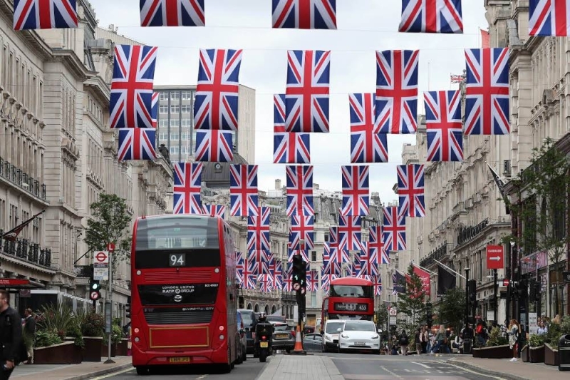 Red London buses pass beneath Union flags, put up to celebrate Queen Elizabeth's Platinum Jubilee, in Regent Street in central London. — AFP pic