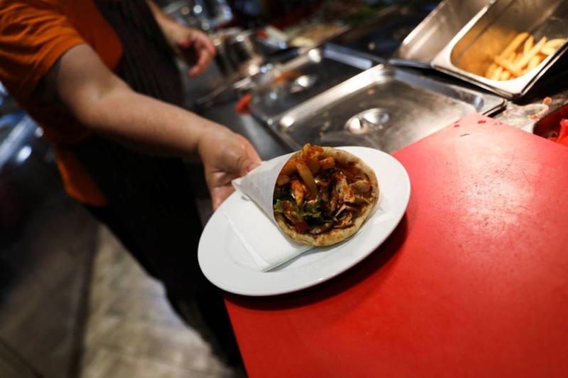 A cook holds a plate of souvlaki, a popular Greek fast food made with pieces of meat grilled on a skewer, in a restaurant, in Athens May 27, 2022. — Reuters pic