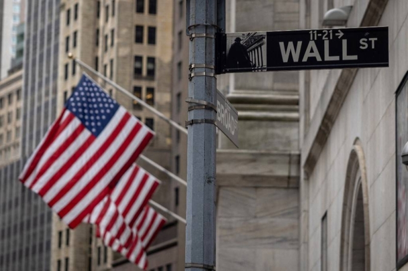 Sebuah tanda menunjuk ke Wall Street dengan bendera AS di luar New York Stock Exchange di New York pada 16 Juni 2022. - AFP