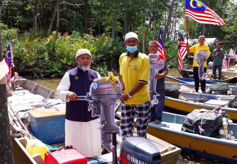   马来西亚渔业发展局（LKIM）主席拿督赛阿布侯辛哈菲兹阿卜杜勒法萨尔（左）于 2022 年 6 月 26 日在马当甘榜德布向渔民移交舷外发动机。 — Bernama pic