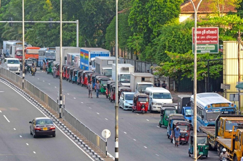 Motorists queue along a street to buy fuel at a fuel station in Colombo on July 3, 2022. — AFP pic