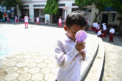School’s out: How climate change threatens education A student uses a portable fan to keep cool outside the classroom during a heatwave at a primary school in Banda Aceh on May 7, 2024. — AFP pic
