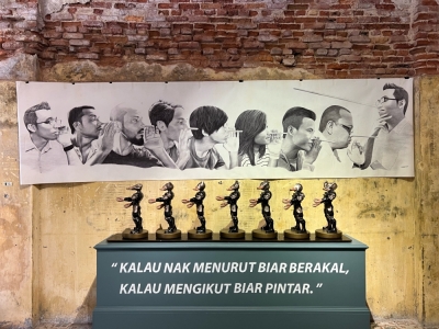 ‘negaraku’: A collectors’ show in Penang that tells the story of Malaysia with various artworks ‘Khabar Angin’ by Syahbandi Samat (background) and ‘Follow the Leader’ by Mohd Al-Khuzairie Ali. — Picture by Opalyn Mok