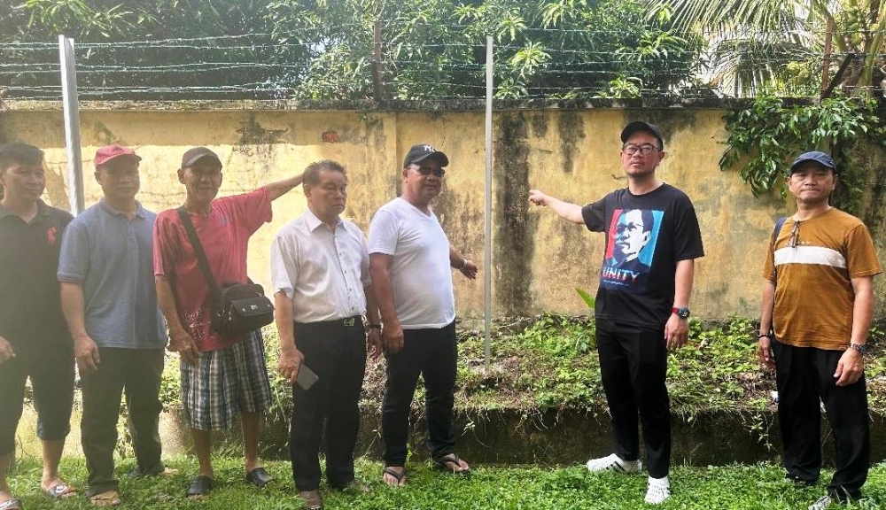 Don’t fence up Tanjung Aru low-cost flats, plead residents Junz (2nd right) points at the fence posts put up several days ago. — The Borneo Post pic