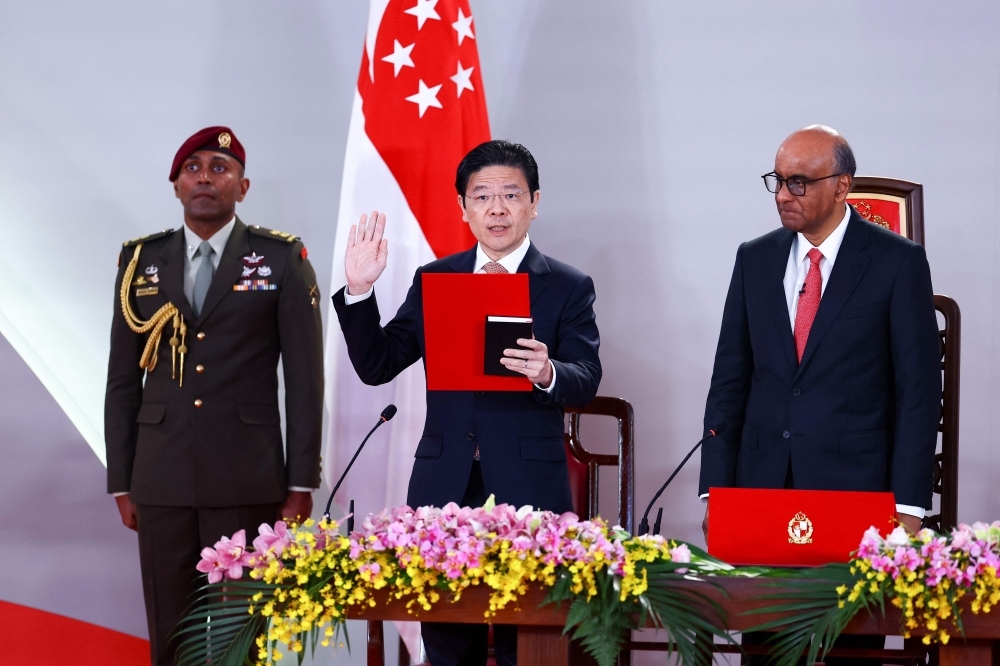 Singapore PM Lawrence Wong, new Cabinet sworn in after PAP election victory Lawrence Wong (centre) is sworn in as Singapore's Prime Minister as Singapore's President Tharman Shanmugaratnam (right) looks on during a swearing-in ceremony at the Istana in Singapore on May 23, 2025. — AFP pic