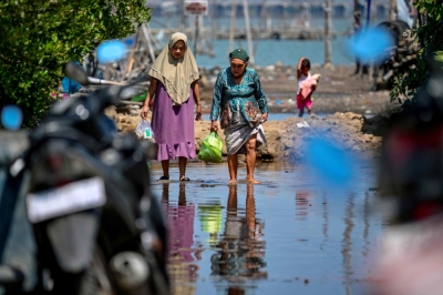 Indonesia’s ambitious seawall plan faces delays as Java villages vanish to rising seas Villagers walk along a flooded road in Bedono, Central Java, on July 30, 2025. Rising seas and sinking land threaten Indonesia’s coast as plans for a massive seawall face delays. — AFP pic