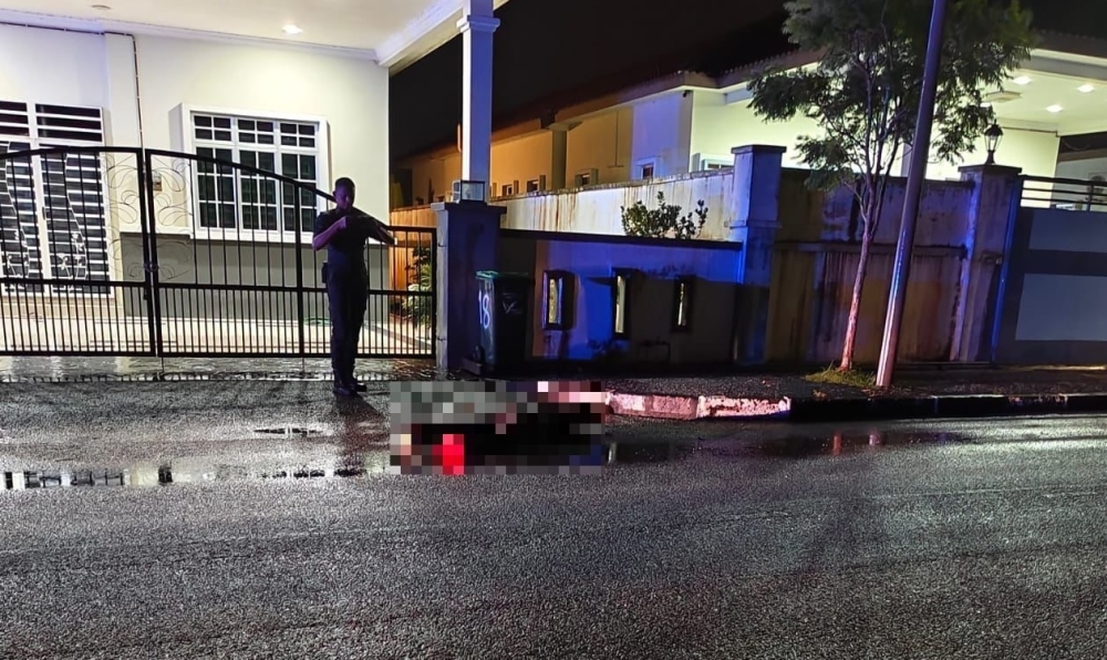 Double murder probe in Guar Chempedak after man and woman discovered with multiple stab wounds A policeman photographs the body of the male victim found on the road in Taman Nona, Guar Chempedak. — Picture via Facebook