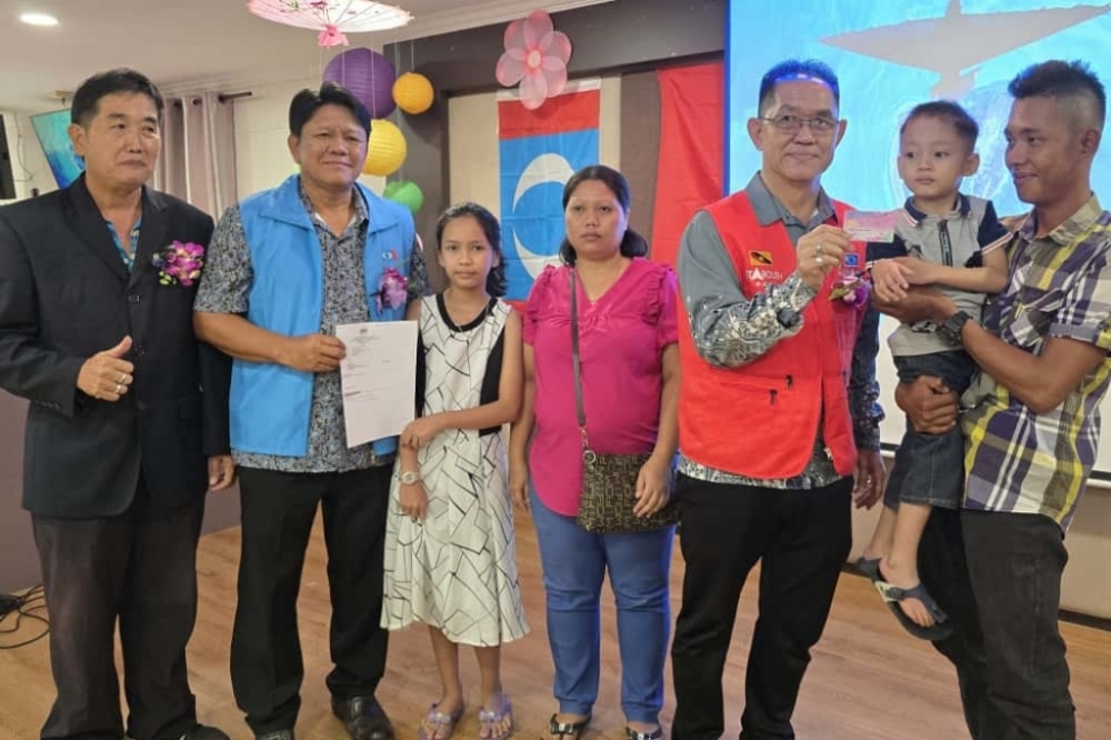 Hopes and dreams rekindle as two Sarawak-born children finally get a shot at school life with ICs Tiang (third right) and Lee (second left) pose with Augustine, Rovina and their parents in an undated photocall. — The Borneo Post pic
