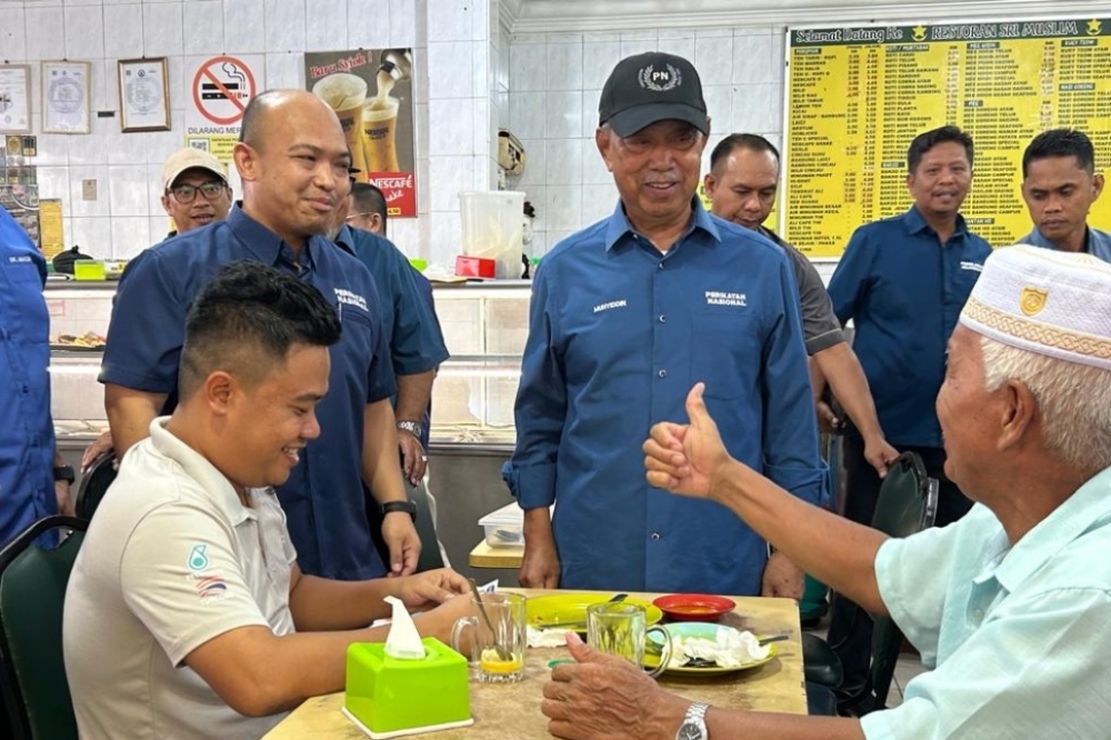 Don’t sell your vote for just RM500, Muhyiddin and first-time Perikatan candidate say on Putatan campaign trail A patron of a mamak shop in Putatan, Sabah gives a thumbs-up to Muhyiddin (standing right) and Dr Afifi during their walkabout on November 21, 2025. — The Borneo Post pic
