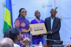 Minister Valentine Uwamariya hands over a laptop to Forever Hyacente Isezerano  the top performer in  national examinations result of Primary school from St Andre in Muhanga district. Dan Nsengiyumva.