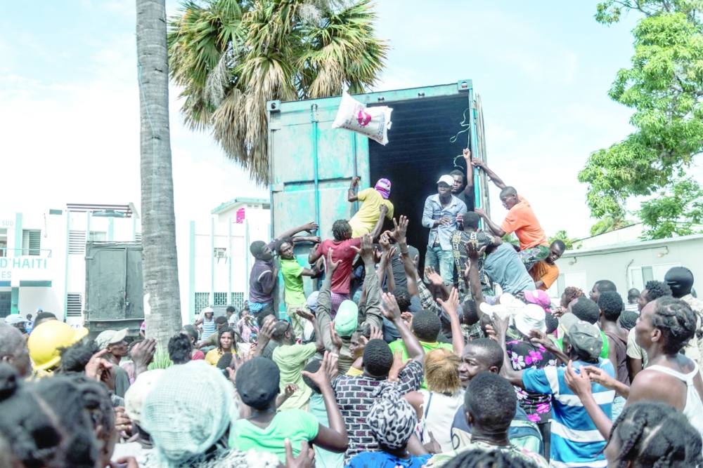 هايتيون منكوبون ينهبون قافلة مساعدات بعد أسبوع على الزلزال المدمر 1 صورة توضح مشاهد الفوضى في ليس كايس، إحدى أكثر المدن تضررا بالزلزال، فيما أكياس الأرز تُلقى على حشود صاخبة