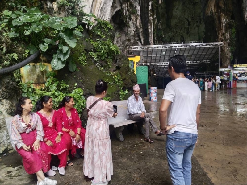 一名妇女在拍照,另一名妇女则在马来西亚的黑风洞观看。照片:THT