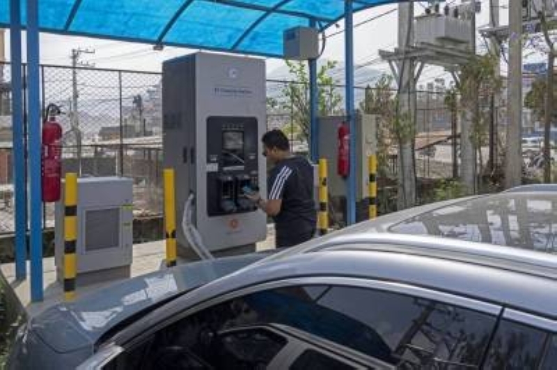 DOSSIER - Un homme charge son véhicule électrique à une borne de recharge à Katmandou, au Népal, le jeudi 14 mai 2024. Photo : AP