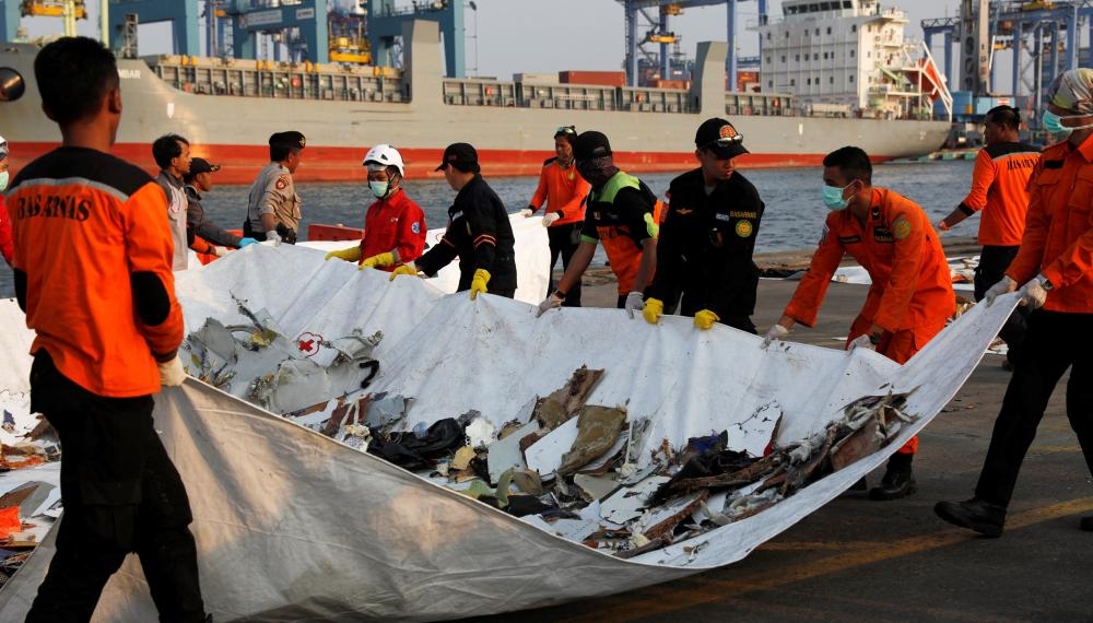 فريق إنقاذ يحمل حطاماً للطائرة الإندونيسية المنكوبة في ميناء بجاكرتا. (رويترز)