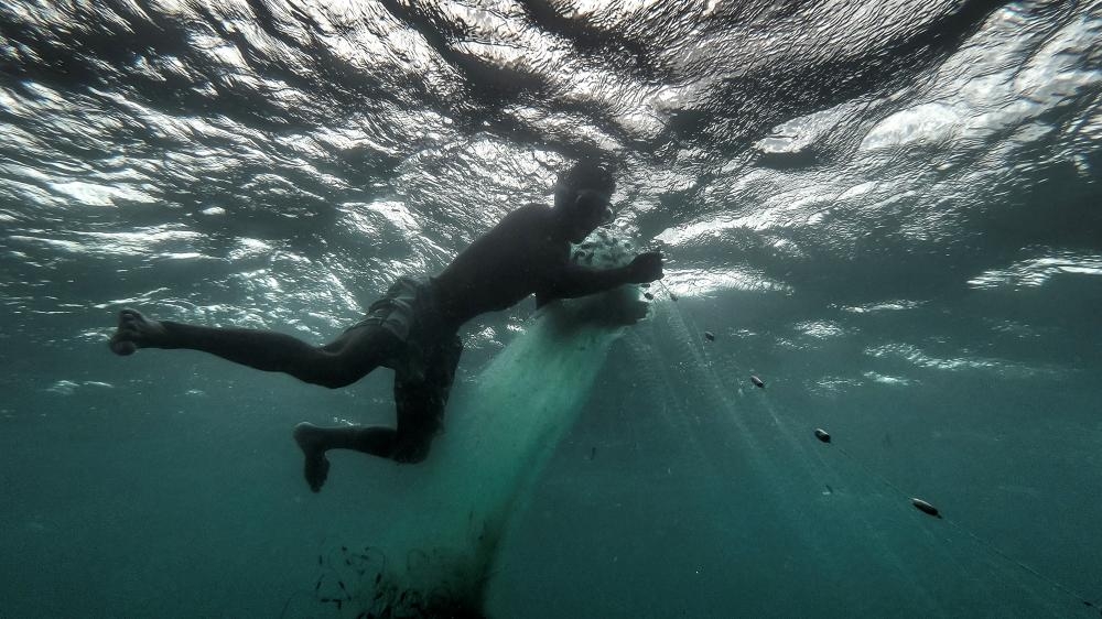 صياد يمسك بشباكه في مياه تجمّع أناكاو للصيد في الصين. (أ ف ب)