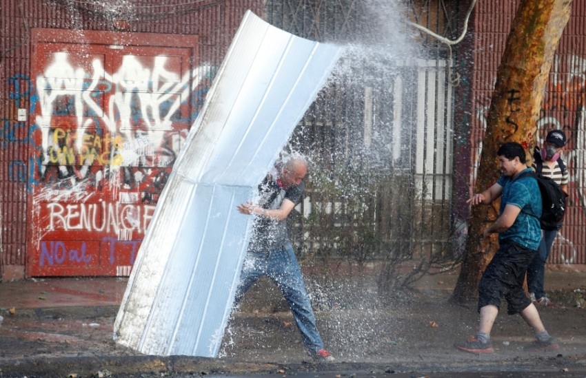 محتجون يغطون أنفسهم من رش الماء في تشيلي
