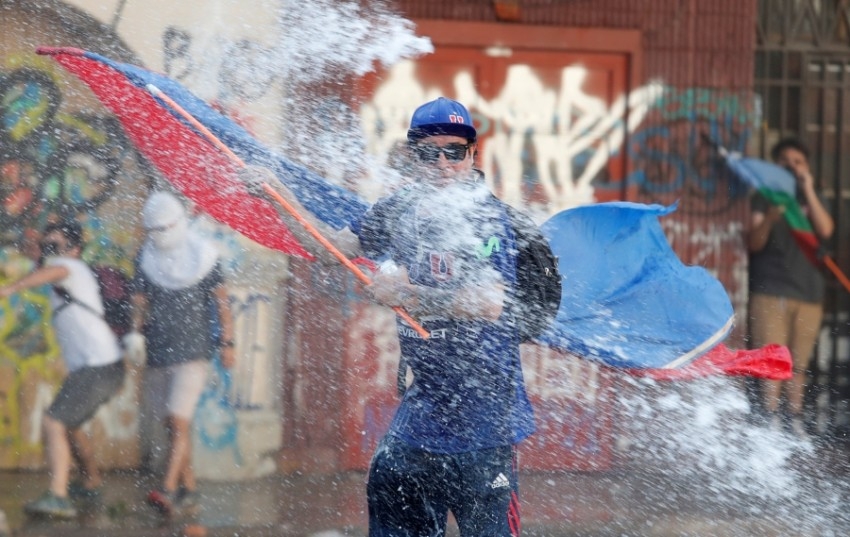 محتجون يغطون أنفسهم من رش الماء في تشيلي