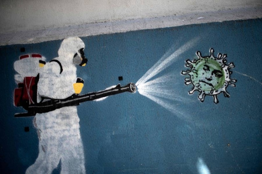 جدارية في أحد أحياء ريودي جانيرو تصور رجل يرتدي بدلة واقية يرش مطهرًا على فيروس كورونا. ( أ ف ب) 
