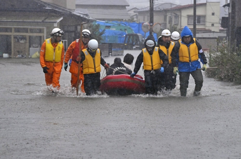 Rescuers pull a boat carrying evacuees in a flooded residential area of the city of Akita on Saturday afternoon.