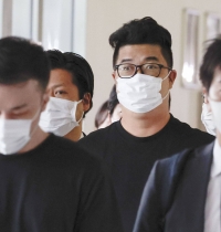Kiyoto Imamura is escorted by police after he arrived at Narita Airport in Chiba Prefecture in February after being deported from the Philippines. | Kyodo