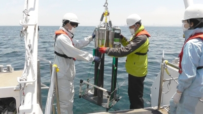 Scientists handle a multiple-core sampling device for extracting sediments and sludge, in Beppu Bay, off Oita Prefecture, in June 2021. Beneath the seawater lie layers of seemingly unremarkable sediment and sludge that tell the story of how humans have fundamentally altered the world around them.