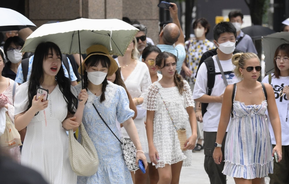 People walk with umbrellas to shade against the sun in Tokyo's Ginza area on Saturday. The Meteorological Agency announced the same day that the rainy season was believed to have ended in the Kanto-Koshin and Tohoku regions.