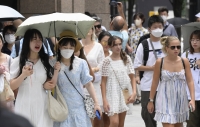 People walk with umbrellas to shade against the sun in Tokyo's Ginza area on Saturday. The Meteorological Agency announced the same day that the rainy season was believed to have ended in the Kanto-Koshin and Tohoku regions. | KYODO