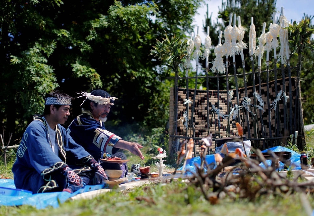 Ainu men sit in front of a makeshift altar to hold a memorial service for Ainu tribesmen defeated by Japanese soldiers in a 15th century battle in Kaminokuni, Hokkaido.