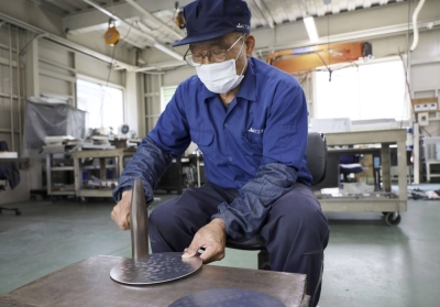 Hiroyuki Fujii, a 78-year-old craftsman at Yamashita Kogyosho, explains the "3D sheet metal forming" method to create the noses of shinkansen trains, in Kudamatsu, Yamaguchi Prefecture, on June 7.