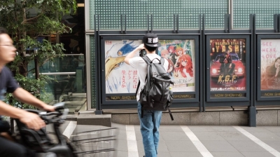 A theater-goer takes a photo of the promotional poster for Hayao Miyazaki’s new film, “The Boy and the Heron.”