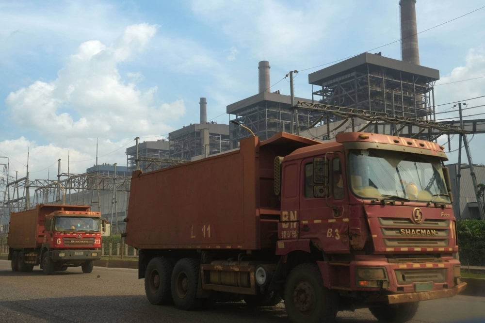 Dump trucks travel in front of a power plant in the Indonesia Morowali Industrial Park.